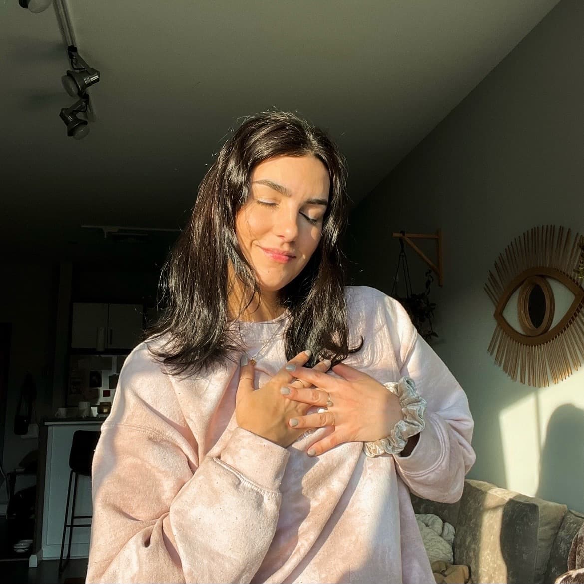 Shannon in golden sunlight, eyes closed, hands resting over her heart